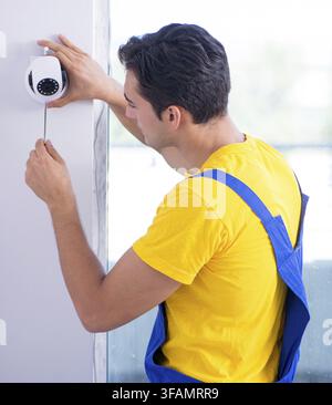 Contractor installs CCTV security cameras in office Stock Photo