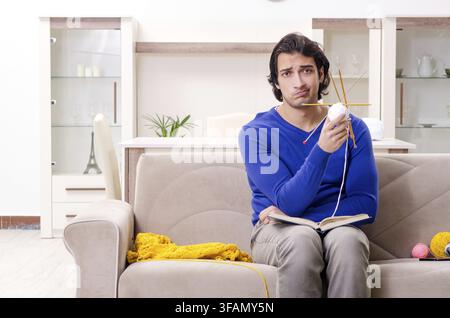 The young handsome man knitting at home Stock Photo