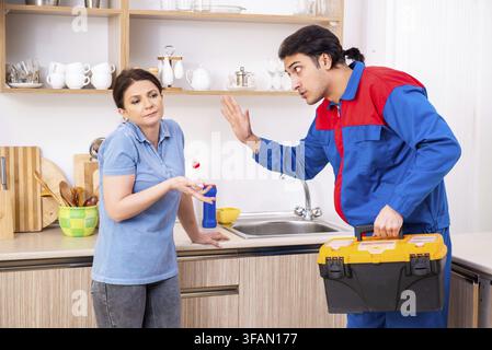 The young male mechanic repairs the faucet Stock Photo