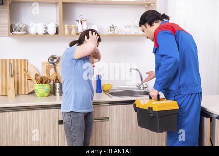 The young male mechanic repairs the faucet Stock Photo