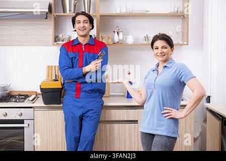 The young male mechanic repairs the faucet Stock Photo