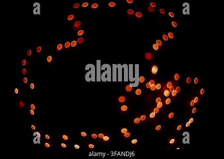 Abstract composition featuring glowing red and orange bokeh light spots arranged against a deep dark background, creating an artistic blurry effect. Stock Photo