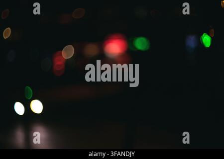 Abstract night photography featuring colorful blurred lights glowing softly against a deep dark background creating a moody atmosphere. Stock Photo
