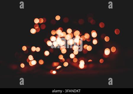 Abstract glowing golden bokeh light dots blurred on a dark black background featuring soft circular spots and warm illumination for festive design. Stock Photo