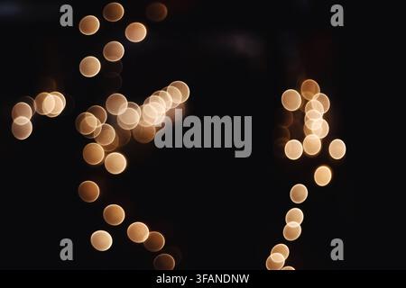 Abstract background featuring golden bokeh circles created by out of focus lights in the dark. Stock Photo