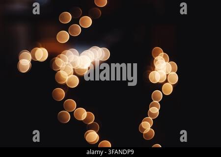 Abstract composition featuring glowing golden bokeh lights creating circular patterns against a dark background. Stock Photo