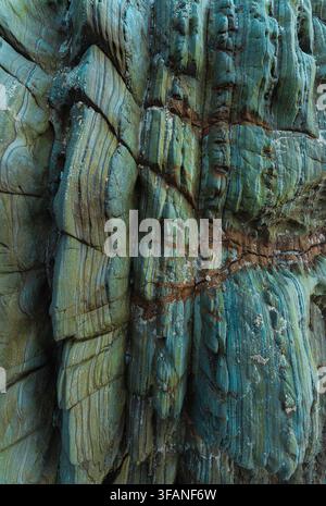 Vertical abstract rock formation with emerald green tones and layered mineral stripes. Detailed geological texture with organic lines and dramatic sur Stock Photo