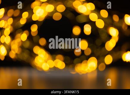Warm golden bokeh lights forming soft circular frame on dark background with central copy space for festive holiday design Stock Photo
