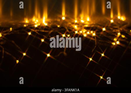 Golden starburst lights scattered across dark reflective surface with glowing trails for festive abstract background and overlay Stock Photo