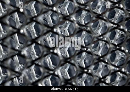 Layered silver metallic mesh in macro view with dark geometric pattern and soft focus for abstract industrial background Stock Photo