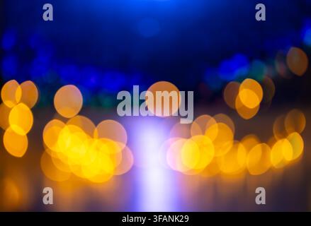 Golden bokeh lights with blue defocused background and central violet glow for festive night abstract background and design Stock Photo