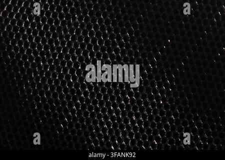 Dark black metallic mesh with subtle silver reflections and repeating hexagonal pattern for moody industrial texture background Stock Photo