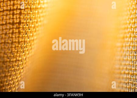 Soft golden abstract background framed by blurred metallic mesh edges with warm glow and central copy space for design Stock Photo