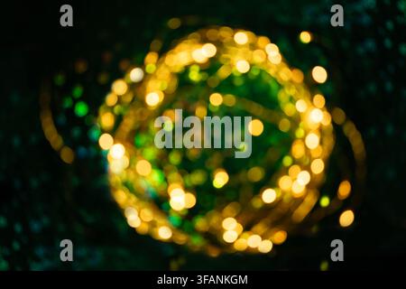 Blurred golden fairy lights forming glowing sphere on dark green background for Christmas New Year or festive design Stock Photo