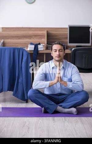 The young handsome businessman is doing exercises at work Stock Photo