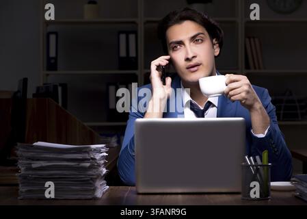 Young male employee working in office at night Stock Photo