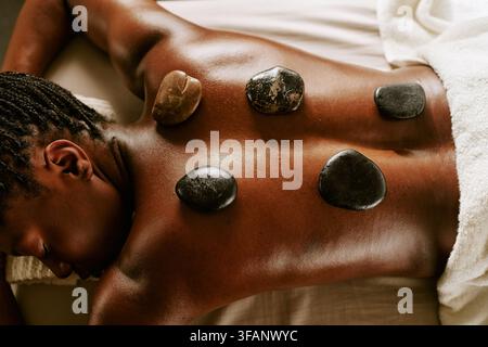 Black Woman Having Hot Stone Therapy on Back in Wellness Spa Stock Photo
