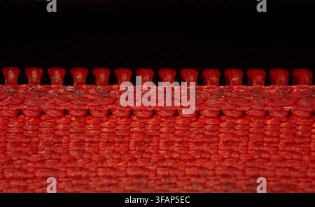 Red Zip Fastener Rising From Red Woven Fabric Edge Stock Photo