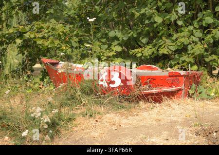 An abandoned old red rowing boat on on land uk Stock Photo