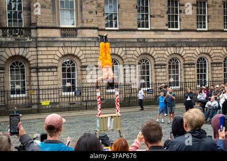 A street performer doing a handstand balancing act on stacked poles during a Edinburgh Festival Fringe street performance, Scotland Stock Photo