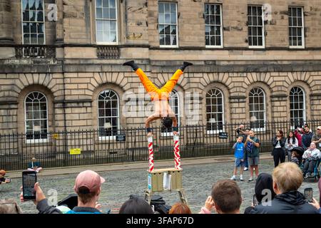 A street performer doing a handstand balancing act on stacked poles during a Edinburgh Festival Fringe street performance, Scotland Stock Photo