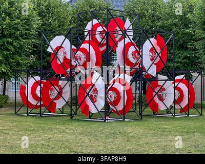 Umbrico Spiral installation at Design Museum Denmark: red and white circular forms framed by black geometric structures on green grass, Copenhagen. Stock Photo