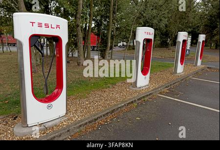 Unused Tesla V2 Supercharger stalls at Gretna Green Services on the A74(M), Scotland, showing twin charging leads in August 2026. Stock Photo