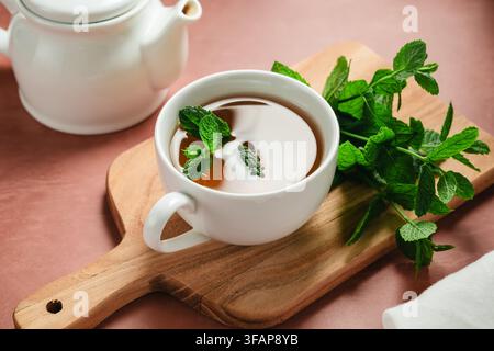 Cup of hot mint tea with fresh leaves on a wooden board Stock Photo
