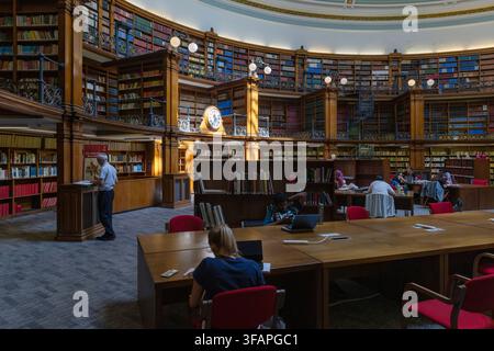 People studying at wooden desks in the historic circular Picton Reading Room surrounded by bookshelves inside Liverpool Central Library, Liverpool. Stock Photo