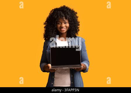 Cheerful beautiful black woman using laptop with empty screen Stock Photo