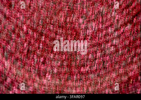 A commercial close-up photograph of vibrant red woolen fabric, highlighting the rich texture, intertwined yarn threads, and intricate knitted pattern. The warm crimson tones and soft fibrous details create an aesthetic and cozy material background. Stock Photo