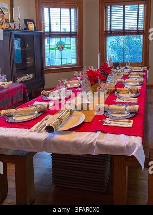 Festive dinner table setting for a family on Christmas with china and a red tablecloth Stock Photo
