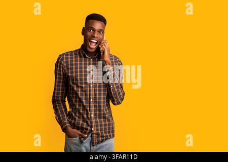 Funny Emotional Black Guy Talking On Cell Phone Over Yellow Background Stock Photo
