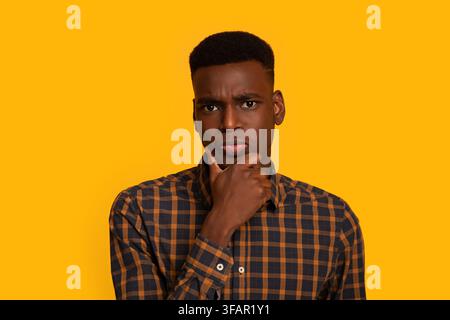 Portrait Of Young Interested Black Guy Touching Chin, Thinking About Offer Stock Photo