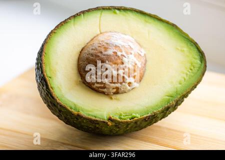 Clean close-up photography of a fresh avocado half centered on a light bamboo surface Stock Photo