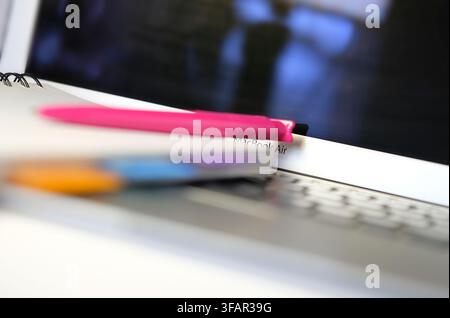 pen and notepad on laptop computer keyboard Stock Photo