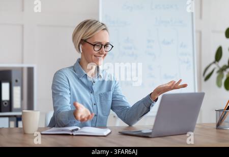 Experienced English teacher giving online lesson on laptop, chatting with students, participating in webinar from home Stock Photo
