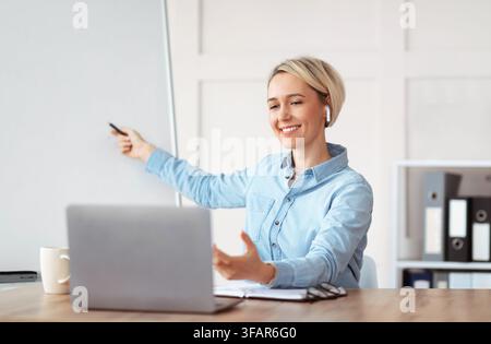 Portrait of millennial teacher giving online lesson on laptop computer from home, mockup for design Stock Photo