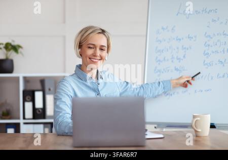 Young university teacher giving mathematics class online from home, explaining logarithms to college students Stock Photo