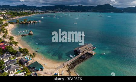 Aerial view of Pigeon island beach featuring boats, sandy shore, and clear water with distant hills in Saint Lucia Stock Photo