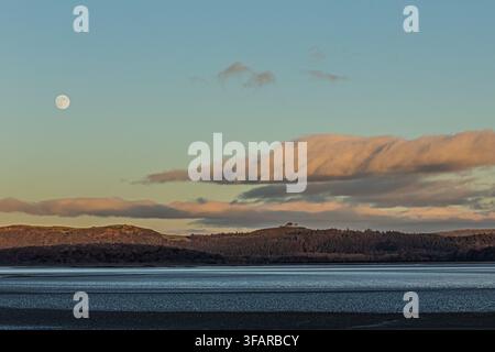 Wolf moon appears in the sky above Morecambe Bay during evening Stock Photo