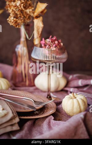 A fall tablescape with white pumpkins, textured plates, a ribbed glass goblet, and a soft linen napkin, creating a warm and rustic atmosphere for seas Stock Photo