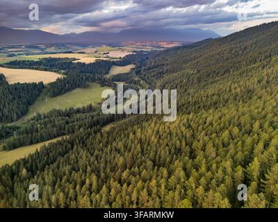 Aerial view of the mountains over Svarin on Cierny Vah valley with dense coniferous forests, rolling hills, and dramatic storm clouds in Kralova Lehot Stock Photo