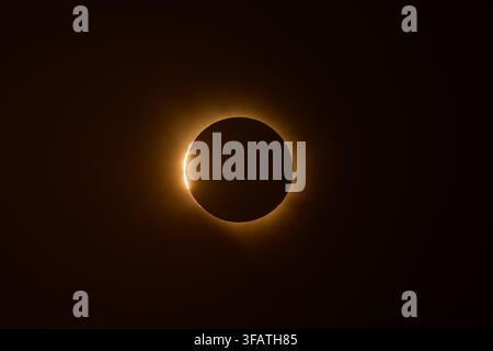 A total solar eclipse with the moon fully covering the sun, showing the glowing solar corona against a dark sky, featuring the brilliant 'diamond ring Stock Photo