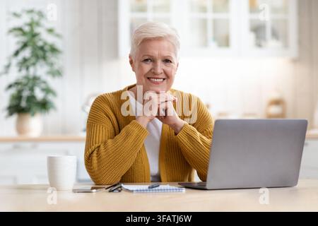 Happy elderly lady waiting for webinar, using laptop Stock Photo