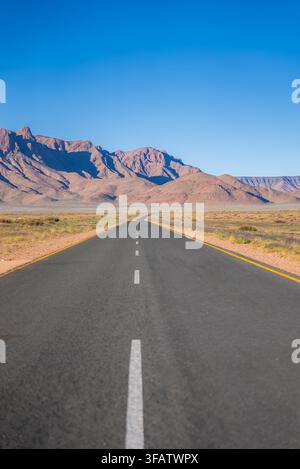 Straight paved road leading through desert mountains in Namibia Stock Photo