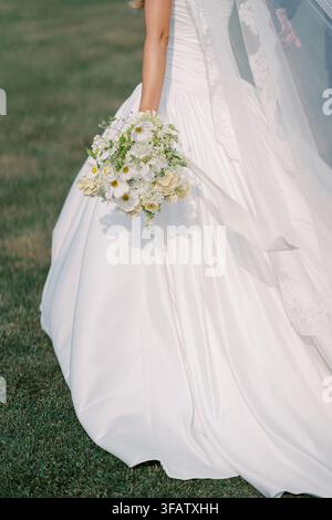 Bride Holding White Flower Bouquet Outdoors on Grass Stock Photo