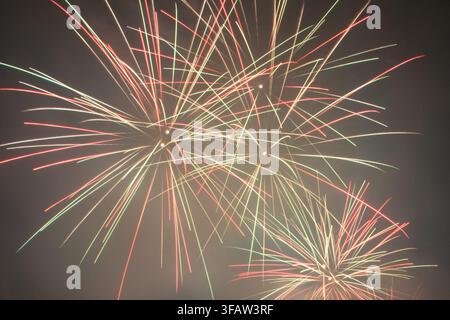 A vibrant closeup of fireworks exploding in the night sky, featuring bright red, green, and golden trails radiating outwards. Ideal as a festive backg Stock Photo