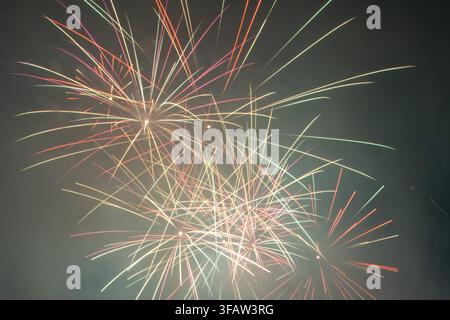 A vibrant closeup of fireworks exploding in the night sky, featuring bright red, green, and golden trails radiating outwards. Ideal as a festive backg Stock Photo