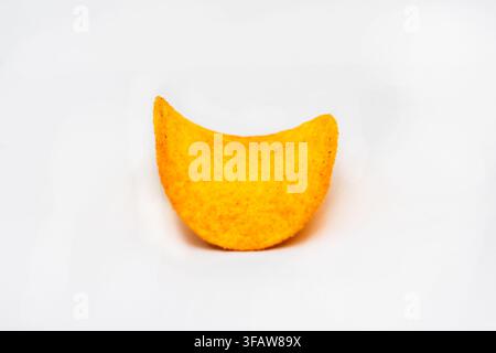 A single curved potato chip is isolated on a clean white background. Stock Photo